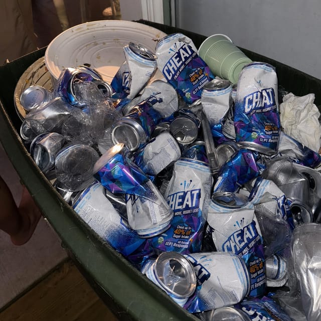 A recycling bin overflowing with crushed aluminium cans after a party, morning light